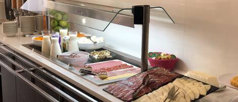 A buffet with various food items, including meats, cheeses, and fruits.