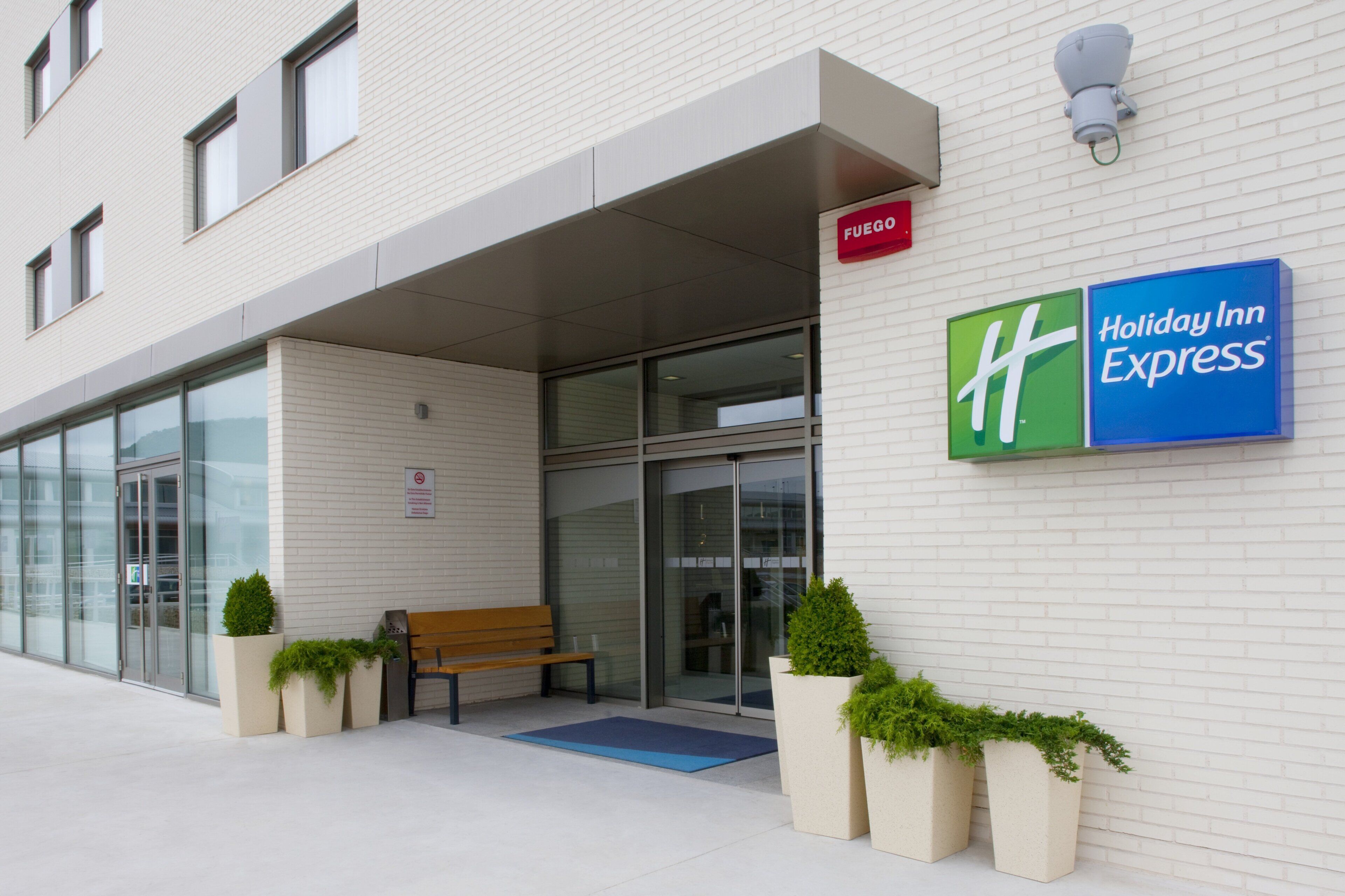 A Holiday Inn Express building with a clear entrance, a bench outside, and potted plants.