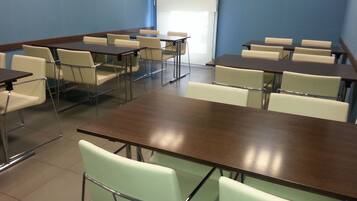 A conference room with multiple tables and chairs, arranged in rows.