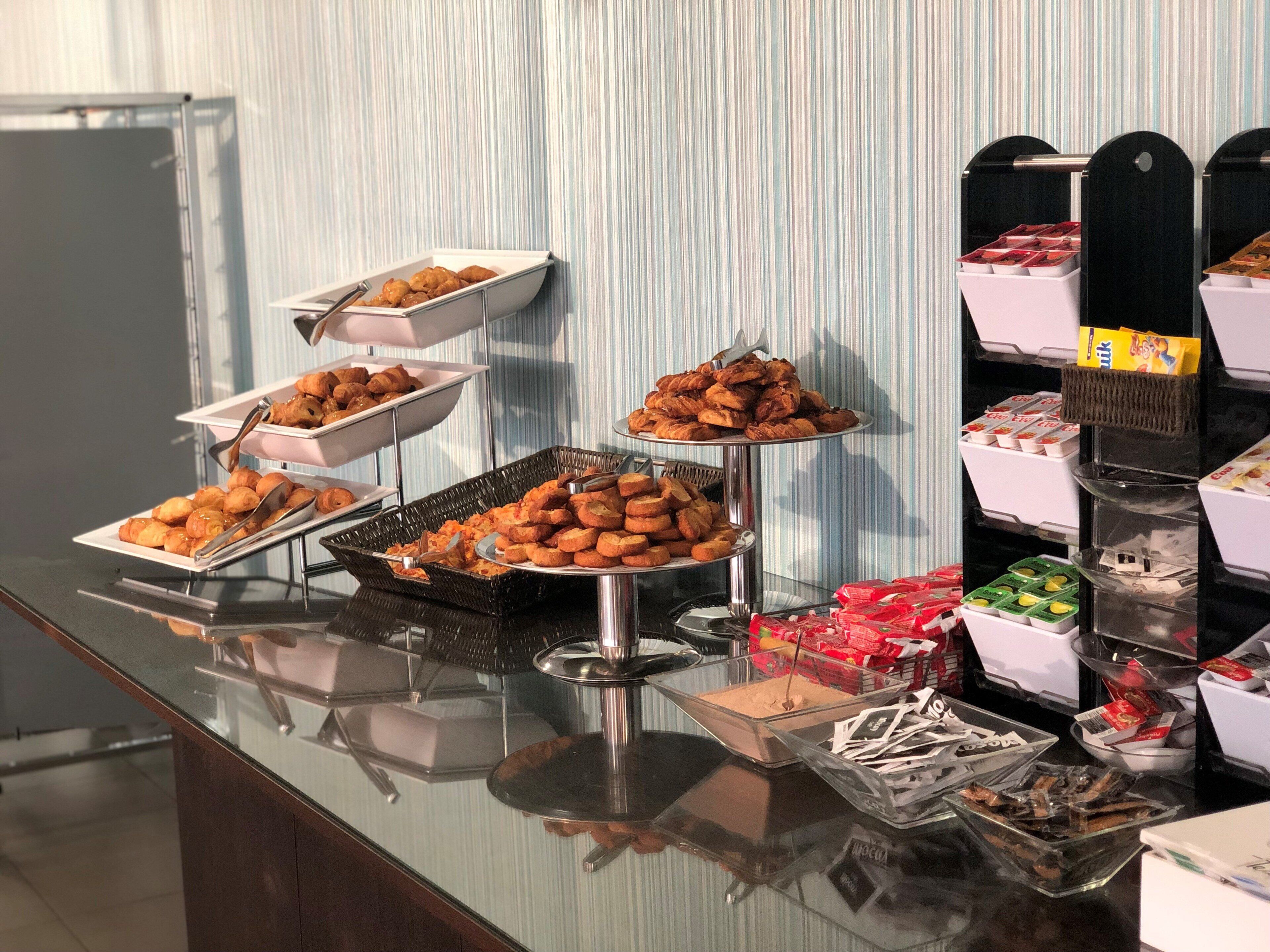A buffet table with various food items and trays.