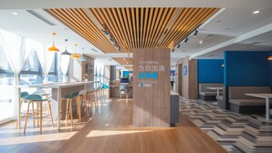 A modern interior with a wooden ceiling, bar area with stools, seating, and a patterned floor. - Holiday Inn Express Tianjin Dongli by IHG (Tianjin)