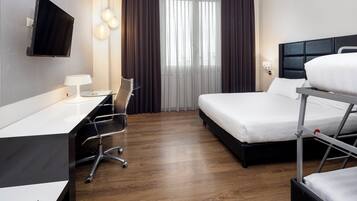 Une chambre d’hôtel avec un lit, un bureau, une chaise, une télévision et une fenêtre avec des rideaux.