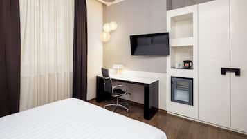 Una habitación de hotel moderna con una cama, un escritorio con una silla, un televisor y armarios empotrados.