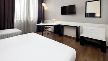 Ein modernes Hotelzimmer mit einem großen Bett, einem Schreibtisch mit Stuhl, einem an der Wand befestigten Flachbildfernseher und einem Nachttisch.
