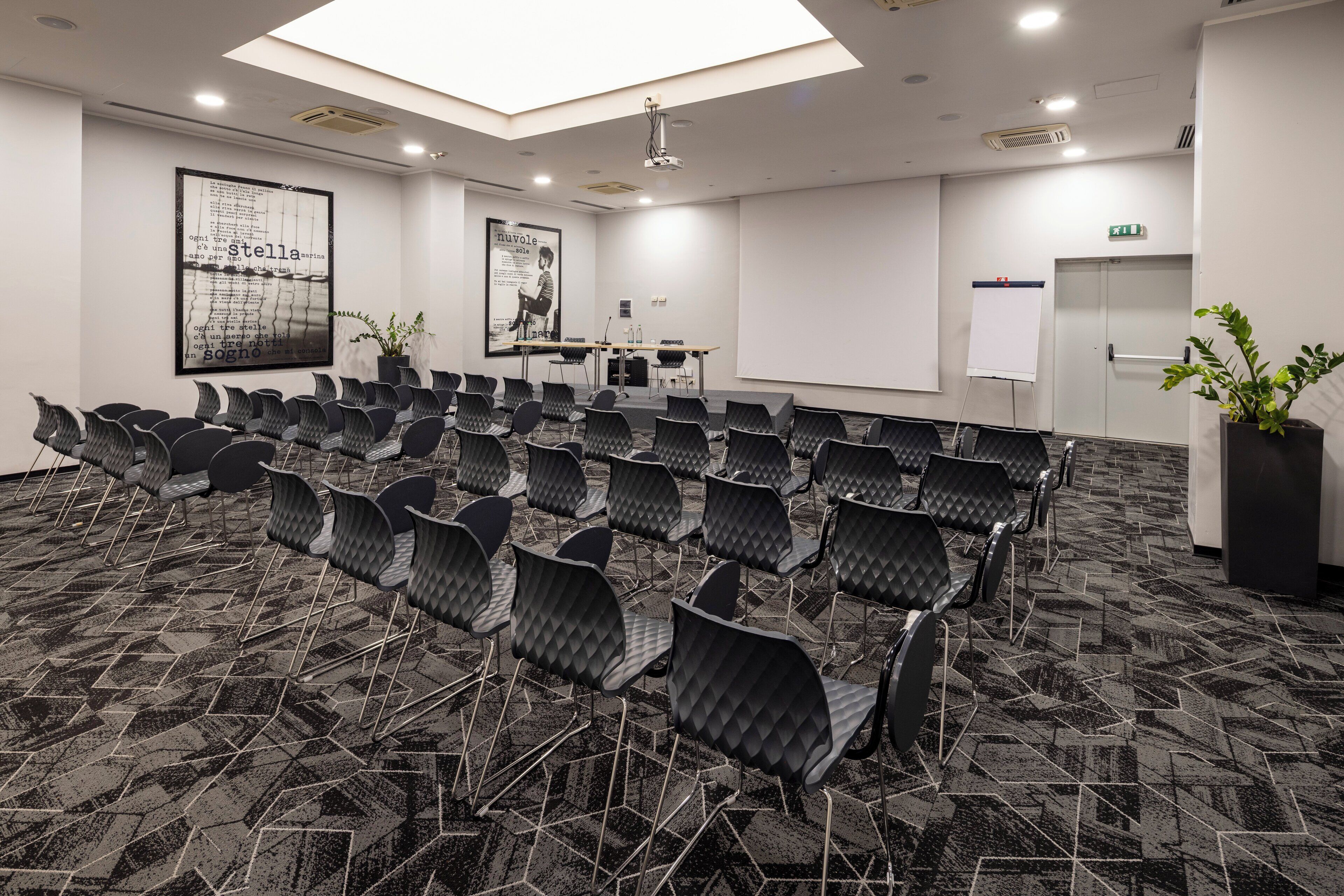 A conference room with rows of chairs, a projector screen, and a whiteboard.