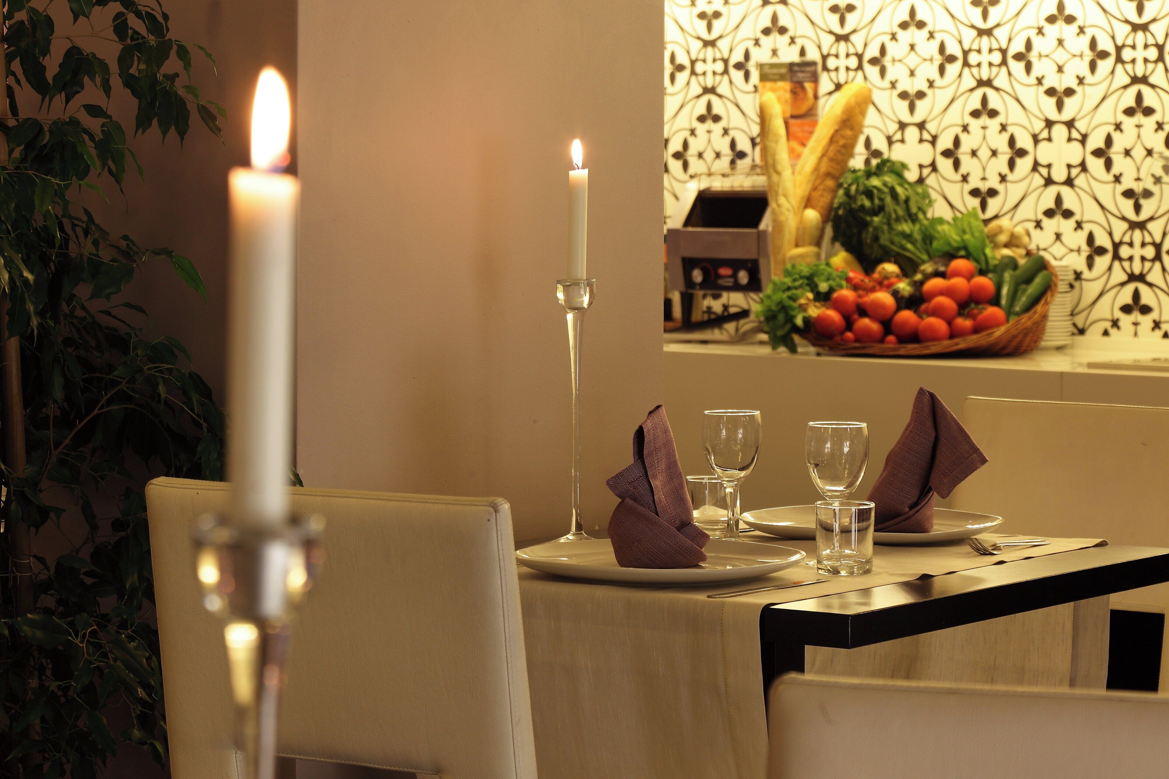 A dining table set with plates, glasses, and a candle.