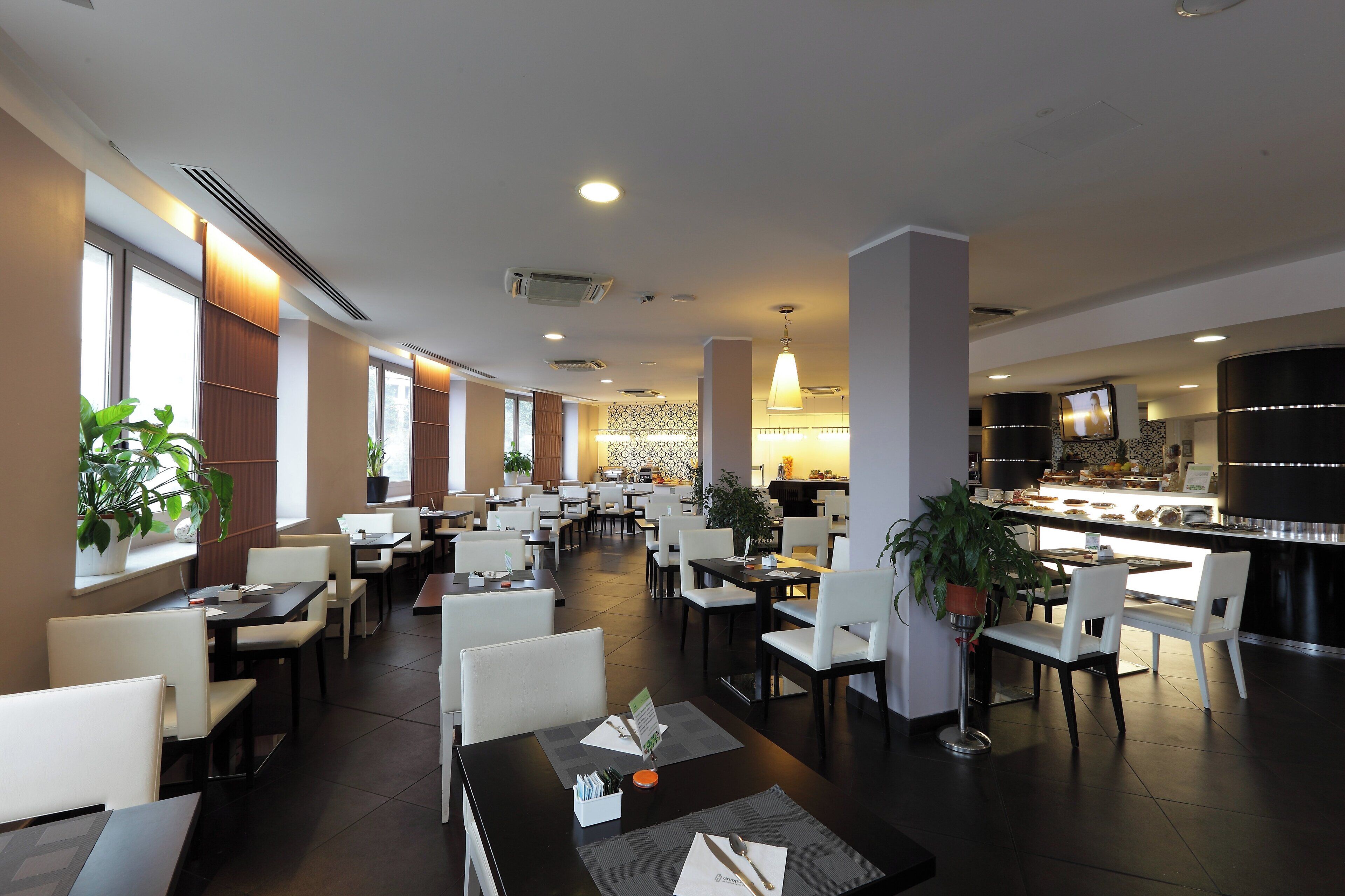 Un restaurant spacieux doté de plusieurs espaces de restauration, notamment des tables, des banquettes et un bar situé à l’arrière-plan.