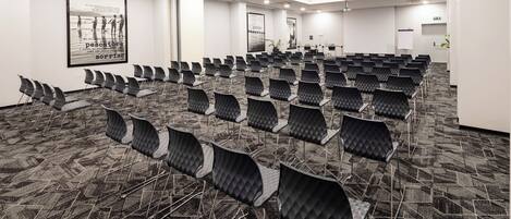 A conference room with rows of chairs, a projector, and a whiteboard.