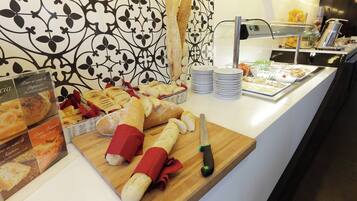 A buffet counter with various bread and pastries, a knife, and a stack of plates.