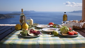 Una mesa servida con comida y bebidas con vistas a un paisaje marino.