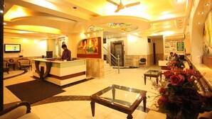 A hotel lobby with a reception desk, a staircase, and a signboard with tourist information. - Hotel Chanchal Deluxe (New Delhi)