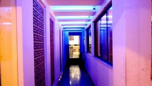 A narrow hallway with a reflective floor, leading to a room with a window and a door at the end. - Hotel Chanchal Deluxe (New Delhi)