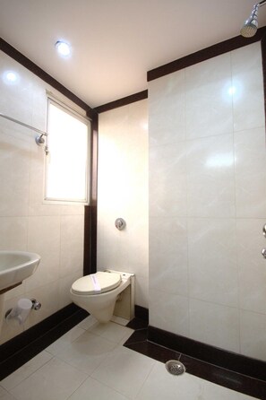 A small bathroom with a toilet, sink, and shower. - Hotel Chanchal Deluxe (New Delhi)