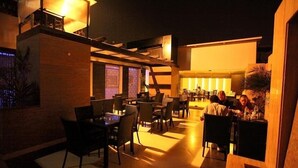 A dimly lit restaurant with tables and chairs arranged for dining. - Hotel Chanchal Deluxe (New Delhi)