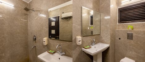 Un baño moderno con ducha, dos lavabos, inodoro y espejo.