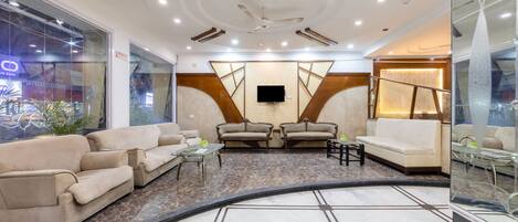 A modern lobby with sofas, a TV, and a patterned floor.