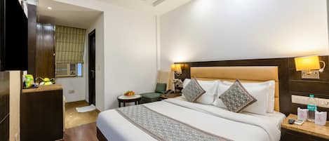 A hotel room with a bed, bedside tables, a desk, a ceiling fan, and a window with curtains.
