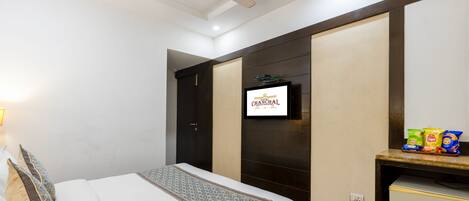 Ein Hotelzimmer mit Bett, Fernseher, Schreibtisch und Snacks sowie einem Deckenventilator.