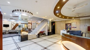 A hotel lobby with a reception desk, a staircase, and a seating area. - Hotel Chanchal Continental (New Delhi)