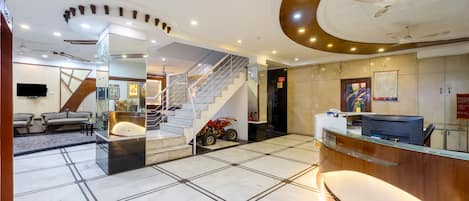 Un vestíbulo de hotel con una recepción, una escalera y un área de descanso.