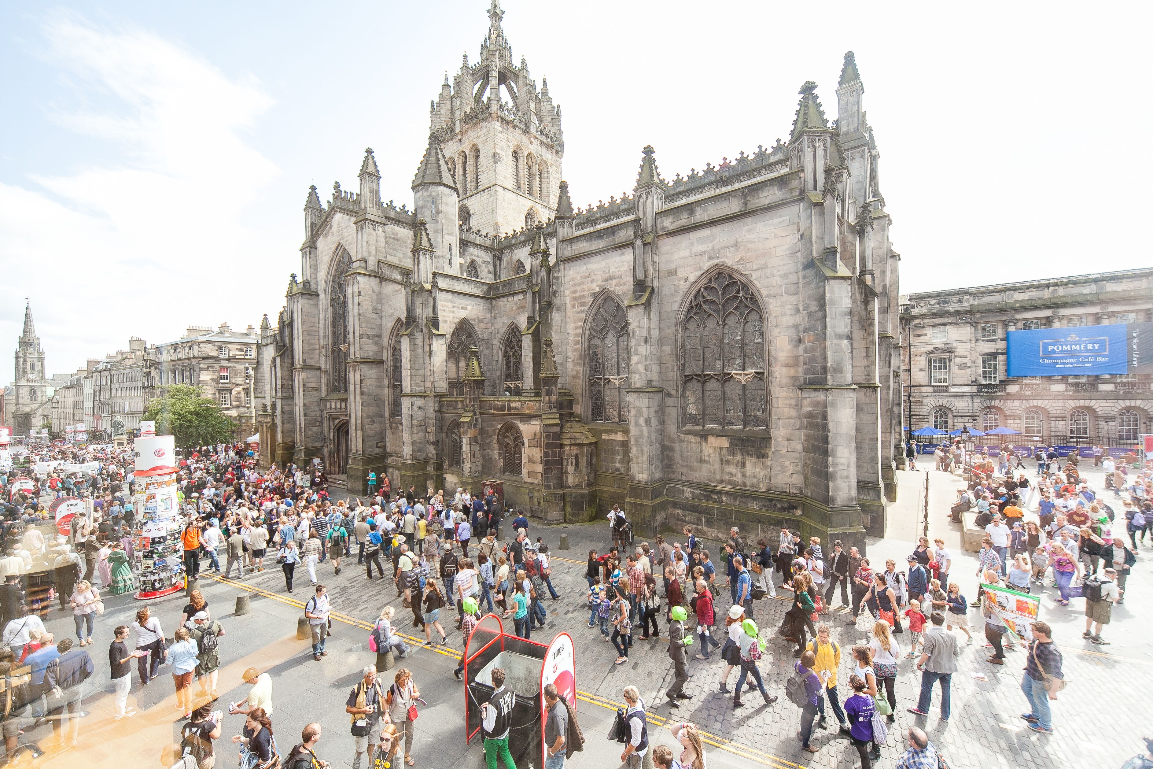 A historic cathedral with Gothic architecture, a bustling crowd, and a prominent blue sign.