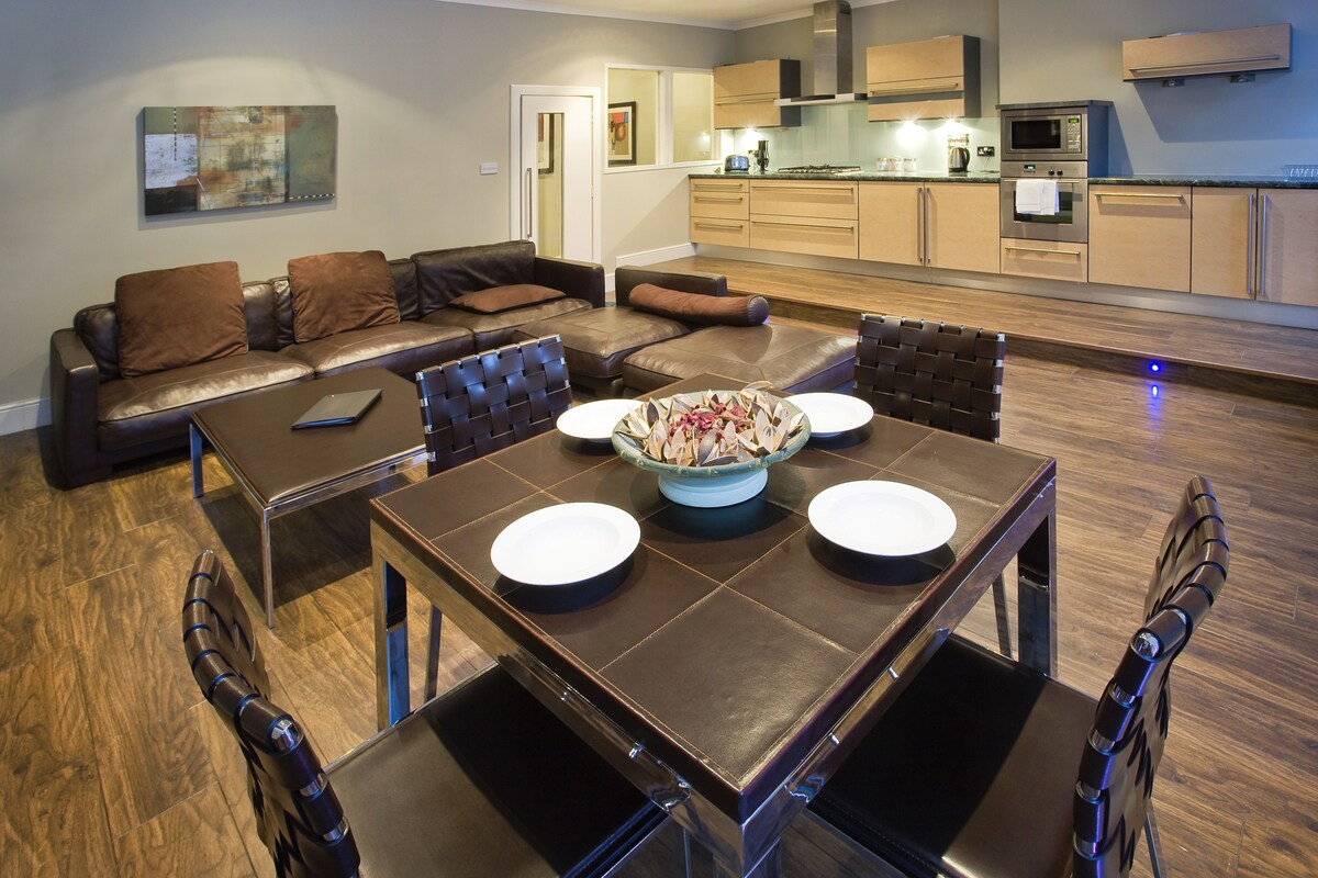 A modern living room with a dining area, featuring a sofa set, a coffee table, and a dining table with chairs.