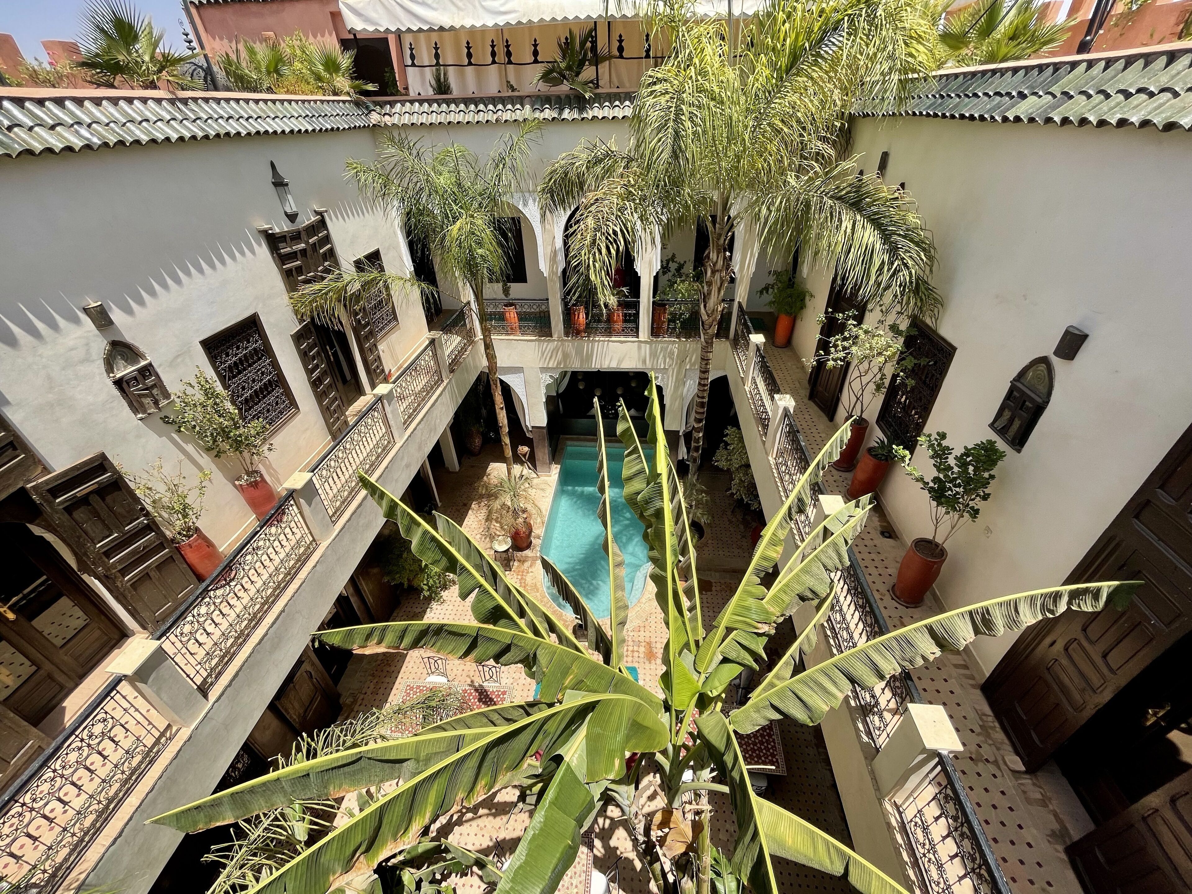 Un patio con piscina, plantas en macetas y un estilo arquitectónico tradicional.
