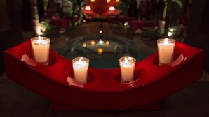 A red candle holder with three lit candles on a reflective surface.