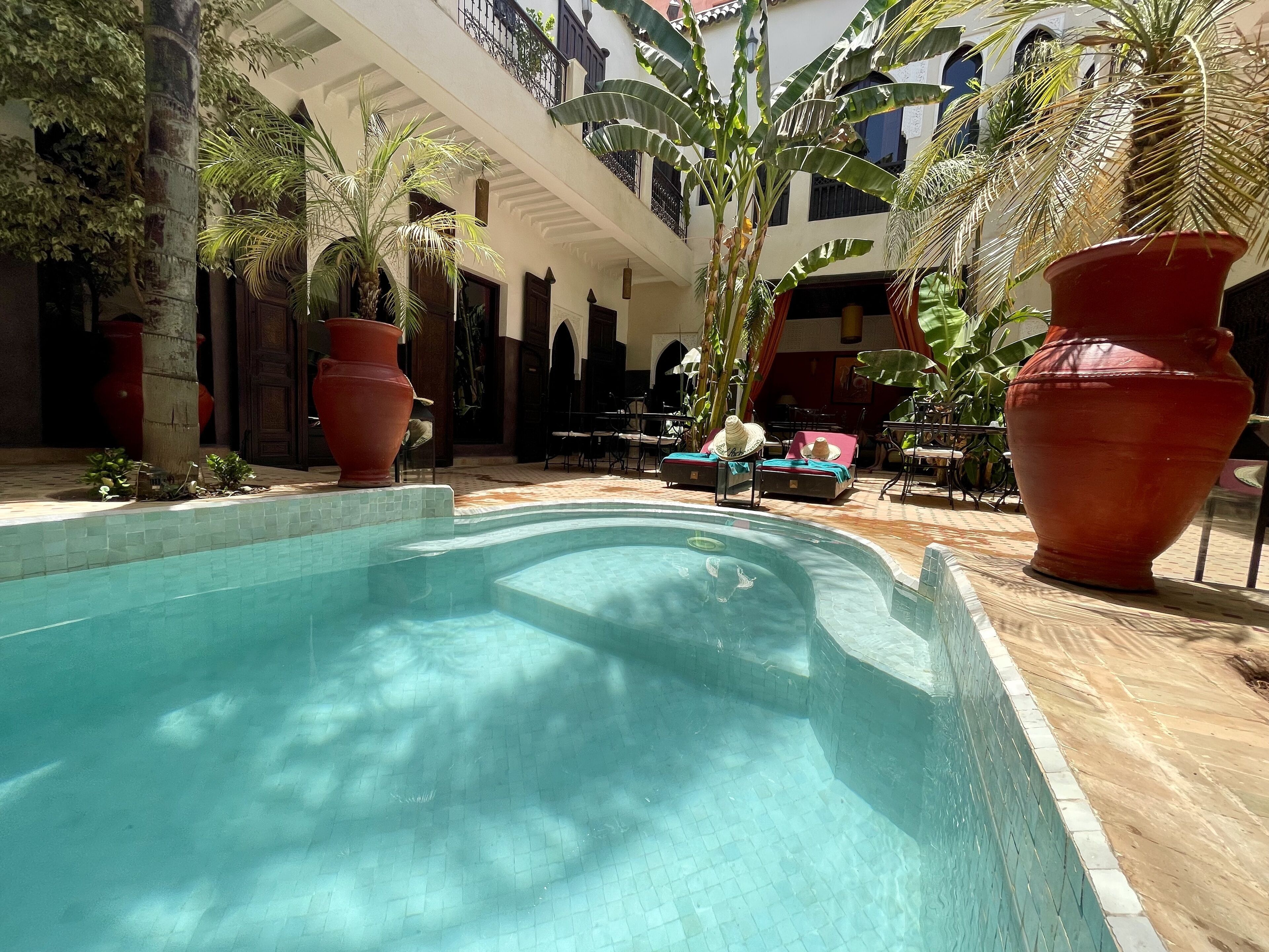 A pool area with lounge chairs and large vases.