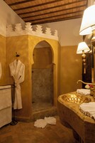 Un baño con bañera, ducha y lavamanos. Hay toallas y una bata colgadas en un perchero.