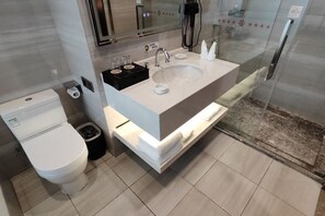 Casa de banho moderna com lavatório branco, sanita e cabine de duche em vidro.