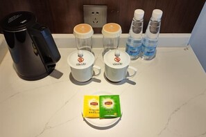 A coffee maker, two cups, two Lipton tea packets, and two water bottles on a countertop. - Yuquan Island Hotel (Nanchang)