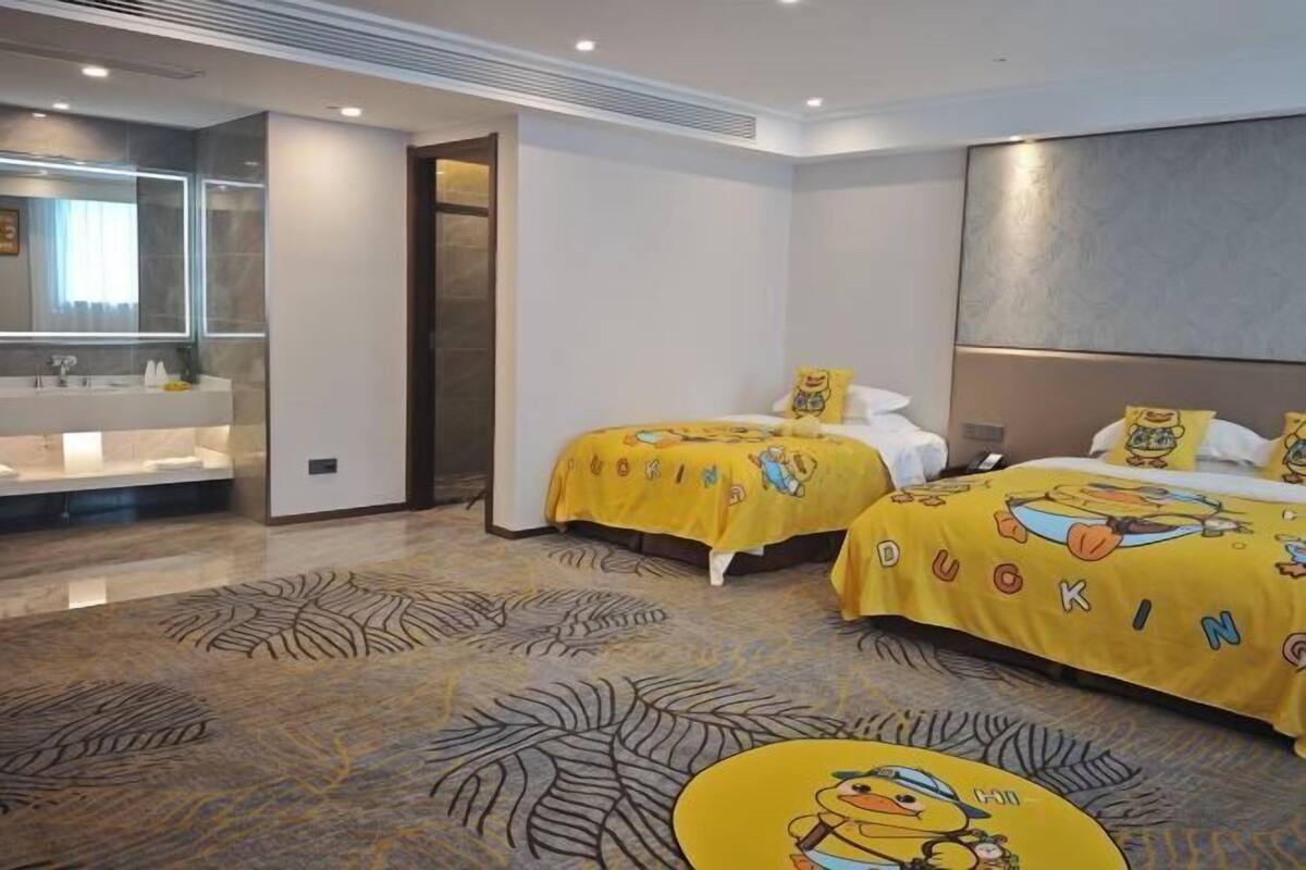A hotel room with two beds, a large mirror, a bathroom with a sink, and a patterned carpet.