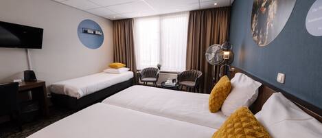 A hotel room with two beds, a desk, a chair, a TV, and a large window with curtains.