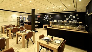 A restaurant with multiple tables and chairs, a counter with a coffee machine, and a wall decorated with plates. - Hotel de Koophandel (Delft)