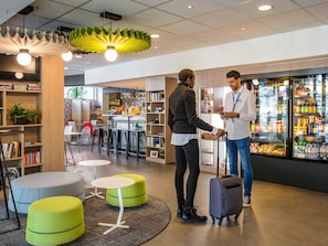 Una biblioteca moderna con estanterías, zonas de descanso y un bar de aperitivos.