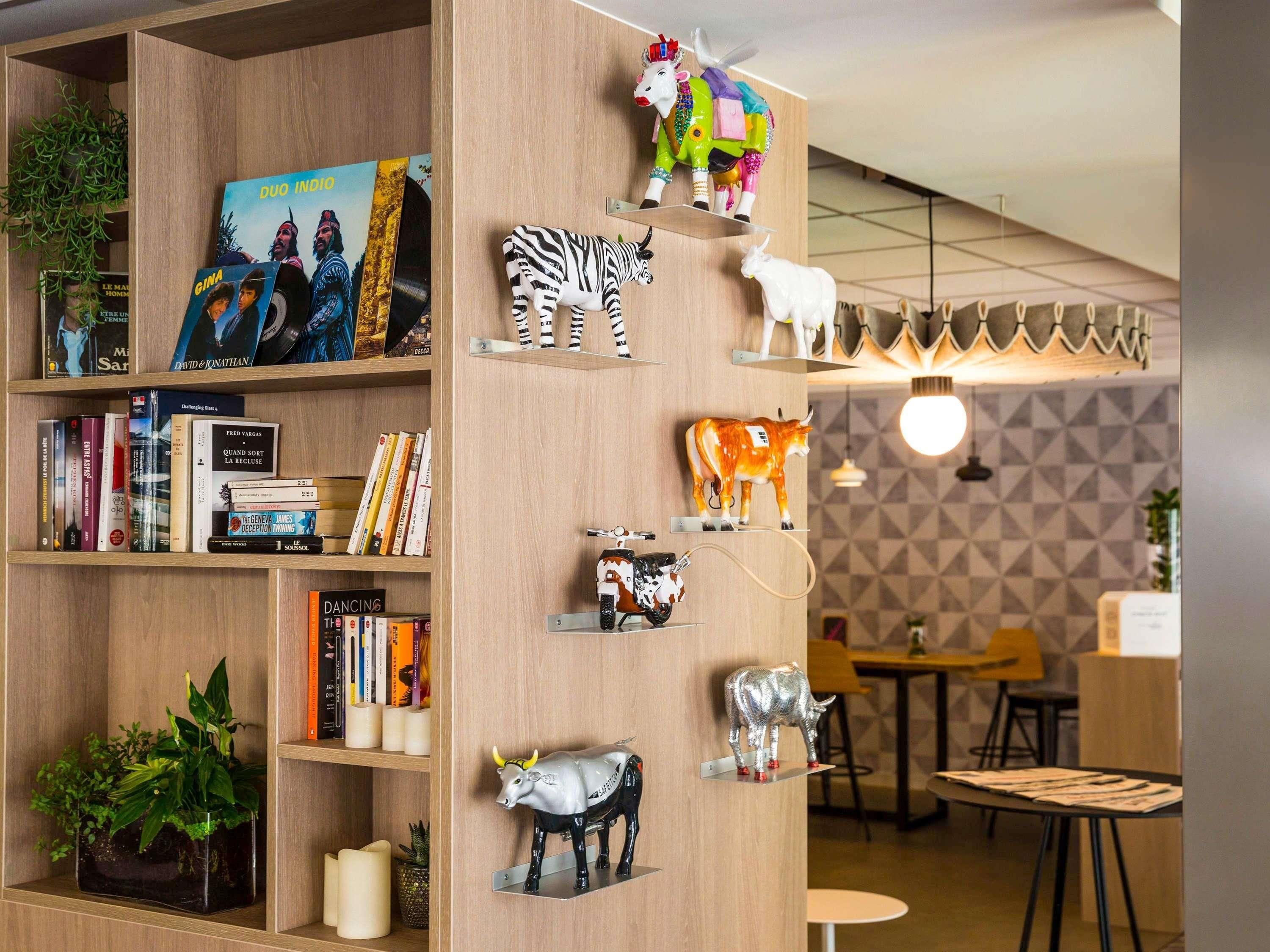 Une bibliothèque contenant divers livres et de petites figurines d’animaux décoratives.