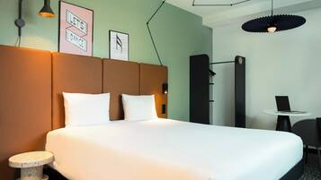 Une chambre d’hôtel avec un lit, un bureau, une chaise et une table ronde.