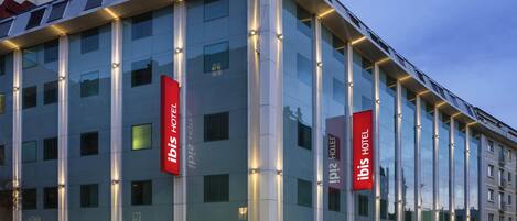 A modern hotel with a glass facade, multiple floors, and prominent signage.