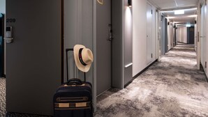 Un pasillo de hotel con puertas numeradas 209 y 211, una maleta y un sombrero en la pared.