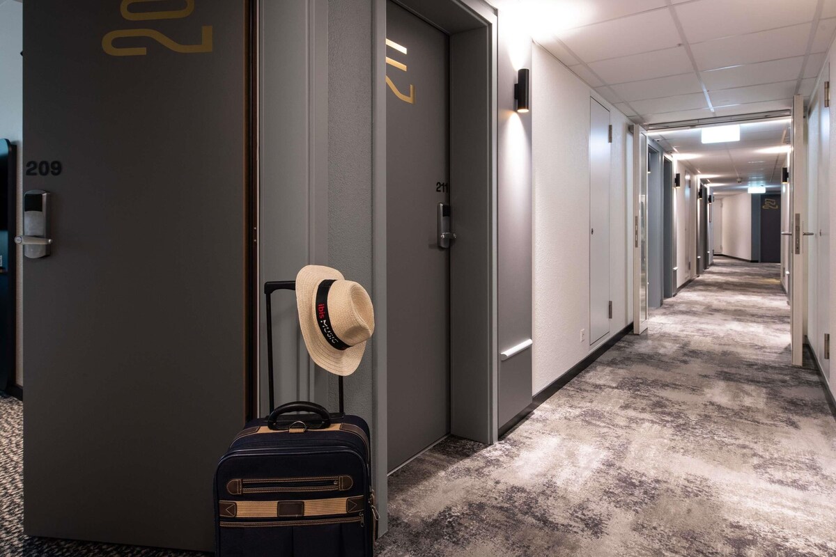 A hotel hallway with doors numbered 209 and 211, a suitcase, and a hat on the wall.