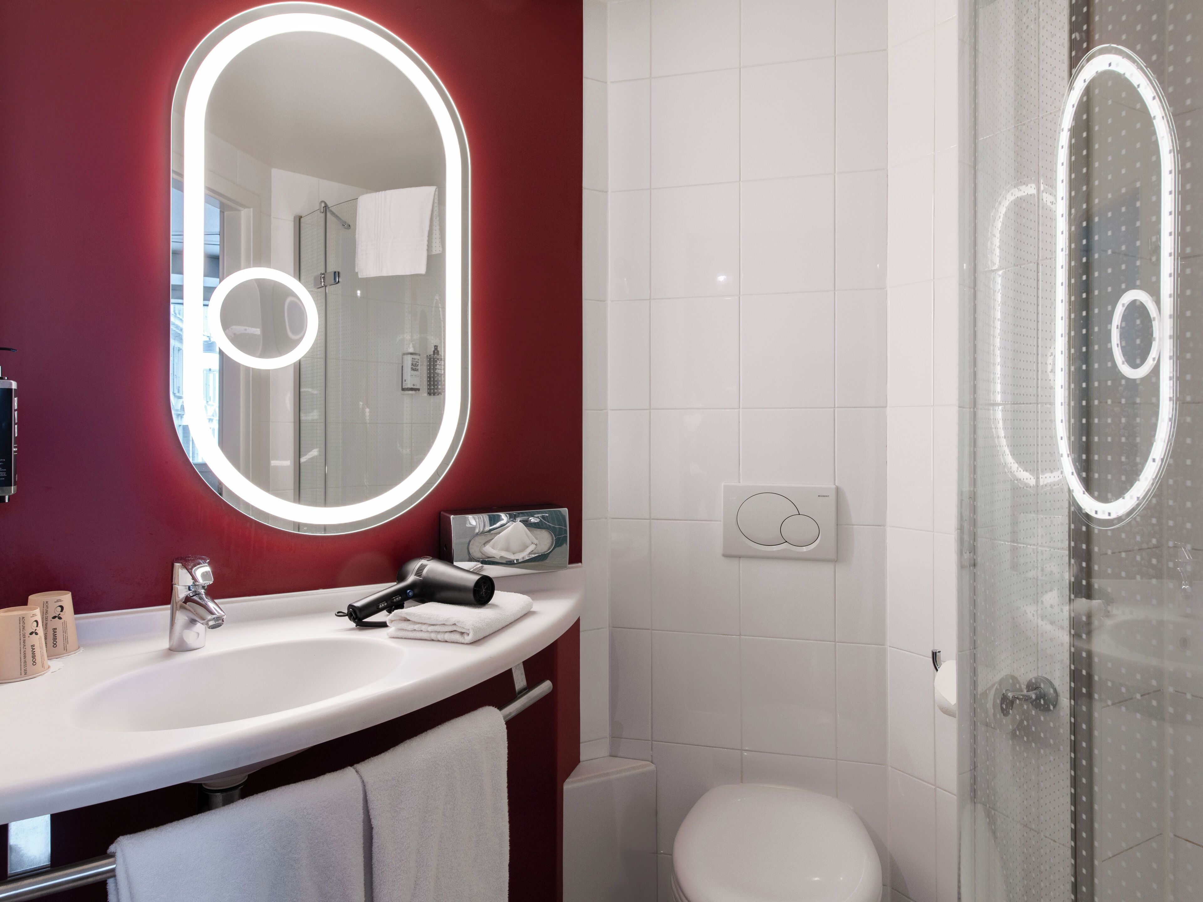 A bathroom with a white sink, a mirror with lights, a toilet, and a shower area.