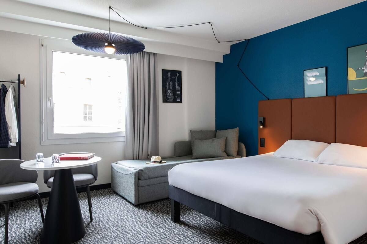 Een hotelkamer met een bed, een bank, een klein tafeltje en een stoel.