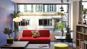 Una sala de estar moderna con un sofá rojo, un reposapiés amarillo, una mesa de centro y una estantería.