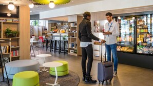 Una biblioteca moderna con estanterías, zonas de descanso y un bar de aperitivos.