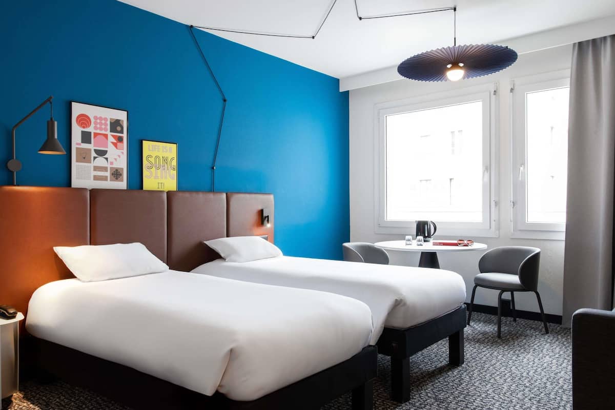 Een hotelkamer met twee bedden, een bureau en een stoel.