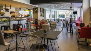 A modern cafe with multiple seating areas, including tables and chairs, and a bar counter with various items.