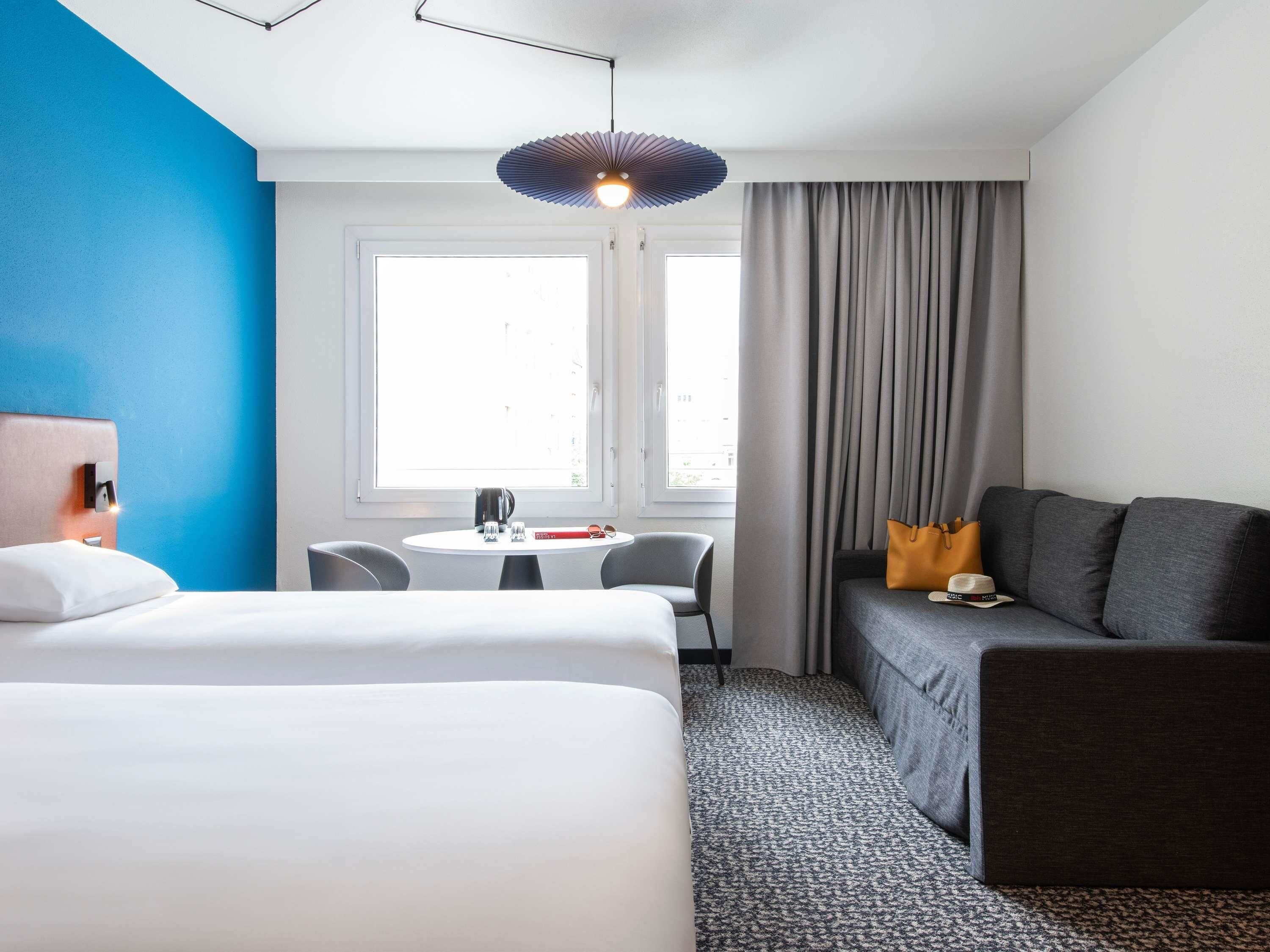 Et hotelværelse med seng, skrivebord, stol, sofa og et vindue med gardiner.