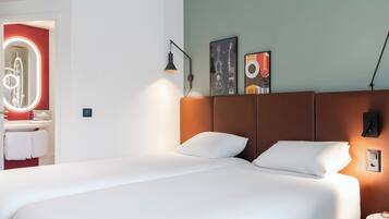 A hotel room with a large bed, a bathroom with a mirror, and a wall with artwork.