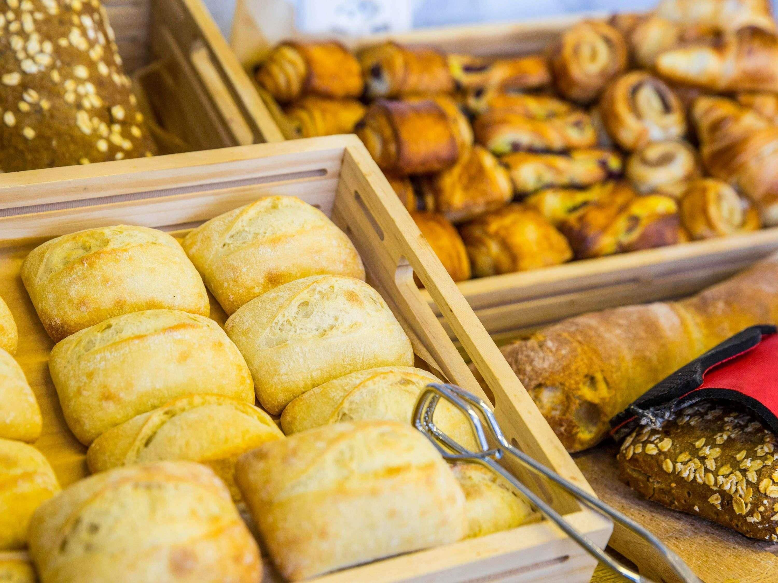 A variety of baked goods in wooden trays, including bread rolls and pastries.